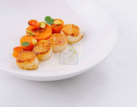 Gourmet seared scallops with herbs and garnish served on a sleek white dish