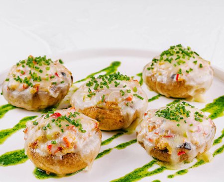 Elegantes champiñones rellenos con relleno cremoso servido en un plato blanco limpio, adornado con hierbas frescas