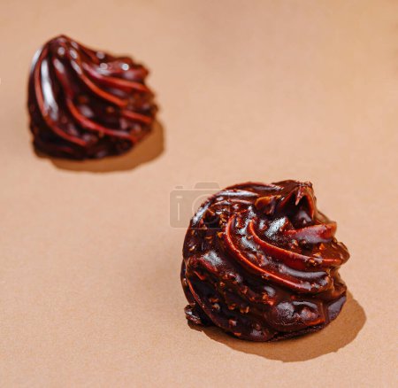 Elegante Strudel aus glänzender Schokolade auf beiger Oberfläche mit minimalistischer Ästhetik