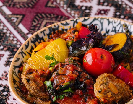 Ragoût d'uzbek salé aux légumes et herbes mélangés, servi dans un bol décoratif sur une nappe à motifs