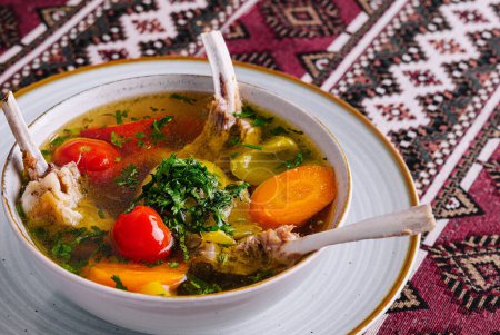 Soupe d'agneau copieux avec des légumes frais, servi dans un bol sur une nappe ethnique dynamique