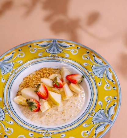 Healthy breakfast oatmeal topped with strawberries and pineapple, served in a decorative bowl