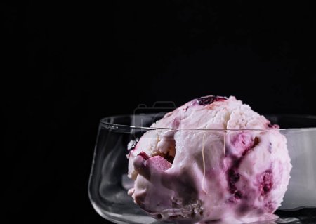 Indulge in a single scoop of berry ice cream presented in a sophisticated stem glass against a dark backdrop