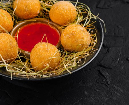 Gourmet fried cheese balls served with dipping sauce on a rustic hay nest plate