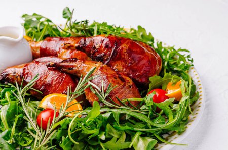 Delicious roasted quail with citrus garnish on a bed of fresh arugula, served on an ornate plate
