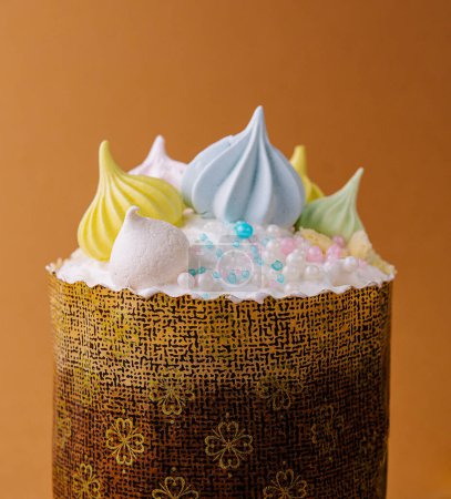 Delicioso mini pastel adornado con merengue colorido y perlas contra un fondo cálido y marrón