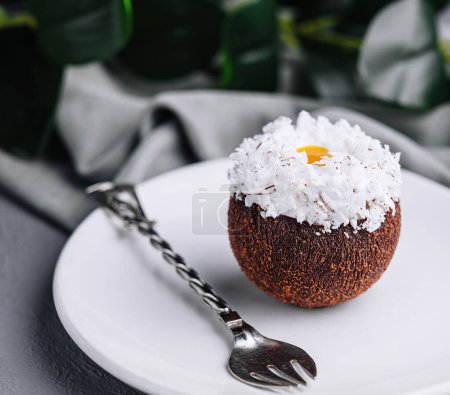 Exquisites Kokos-Dessert auf einem weißen Teller, garniert mit Kokosflocken, gepaart mit einem Tee-Set