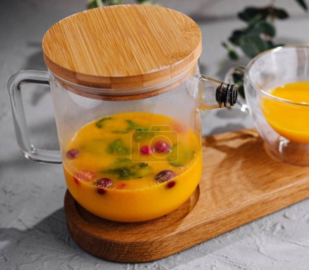 Glass pitcher filled with citrus-infused water, garnished with berries on a wooden tray