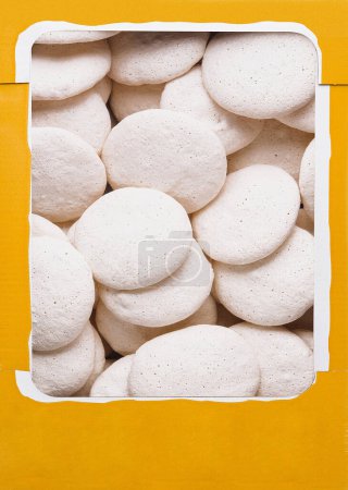 Foto de Vista superior de una caja amarilla abierta llena de galletas caseras de merengue blanco - Imagen libre de derechos