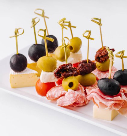 Exquisite Gourmet-Fingerfood-Vorspeisenteller mit einer eleganten Auswahl an Käse. Garnelen. Oliven. Salami. Gurken. Trauben. Und getrocknete Tomaten. Perfekt für das Catering. Parteien. Und Bankette