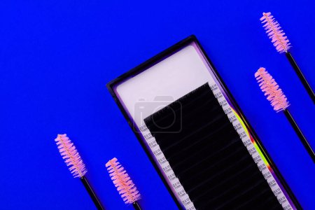 Foto de Vista superior del conjunto de extensión de pestañas con pinceles rosados sobre un fondo azul vivo - Imagen libre de derechos