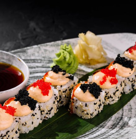 Téléchargez les photos : Des rouleaux de sushi élégants ornés de caviar et de garnitures, servis avec de la sauce soja - en image libre de droit