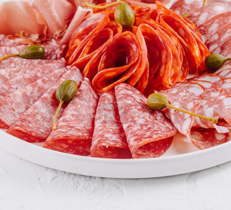 Tantalizing selection of cured meats garnished with capers, presented on a sleek plate