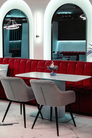 Elegant cafe interior showcasing a chic red velvet sofa, marble flooring, and sophisticated lighting