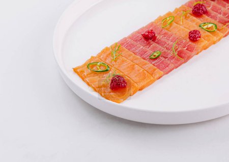 Elegant presentation of salmon sashimi garnished with lime and herbs on a white plate