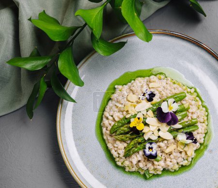 Exquisite plate of risotto garnished with fresh asparagus and colorful edible flowers, artfully presented