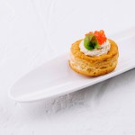 Elegant puff pastry vol-au-vent filled with cream and topped with salmon roe on a white platter