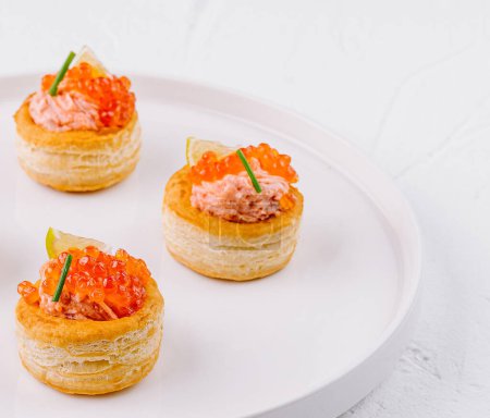 Gourmet puff pastry cups with salmon tartare and herbs, ready to serve on a white background