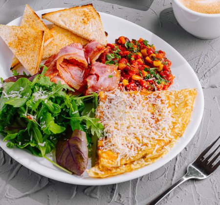 Téléchargez les photos : Petit déjeuner copieux avec omelette, pain grillé à l'avocat, café et légumes frais - en image libre de droit