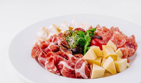 Assorted deli meats and cheese cubes elegantly presented on a white plate