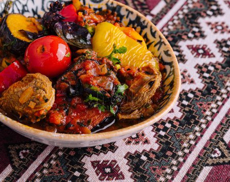 Savory uzbek stew with mixed vegetables and herbs, served in a decorative bowl on a patterned tablecloth