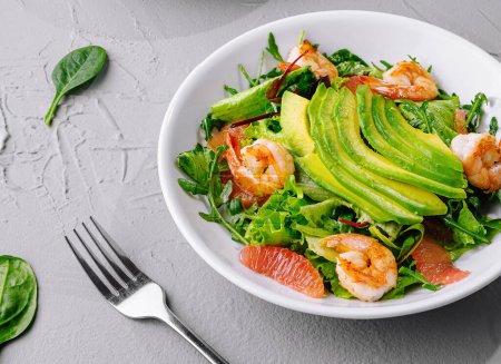 Photo for Bowl of vibrant shrimp avocado salad, perfect for healthy eating, on a gray textured background - Royalty Free Image