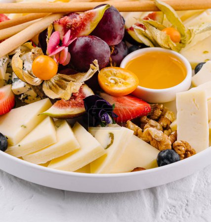 Elegant cheese board with assorted cheeses, fruits, nuts, and honey, ideal for entertaining