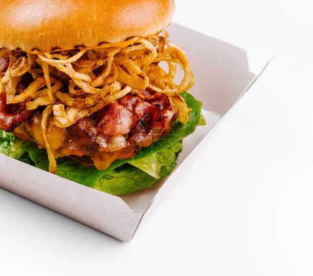 Köstlicher Burger mit Speck und goldenen gebratenen Zwiebeln, präsentiert in einem Papiercontainer