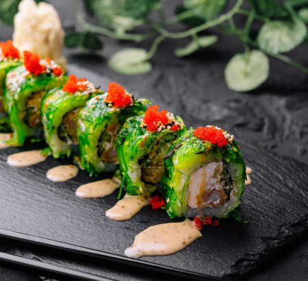 Delectable sushi roll topped with tobiko and spicy mayo on a dark slate