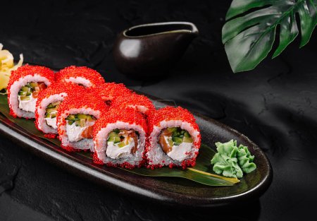 Herzhafte rote Kaviar-Sushi-Rolle mit Ingwer und Wasabi auf stilvollem schwarzem Hintergrund