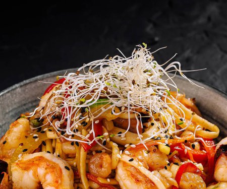 Appetizing seafood stir-fry with shrimp, vegetables, and noodles served on a dark, textured background