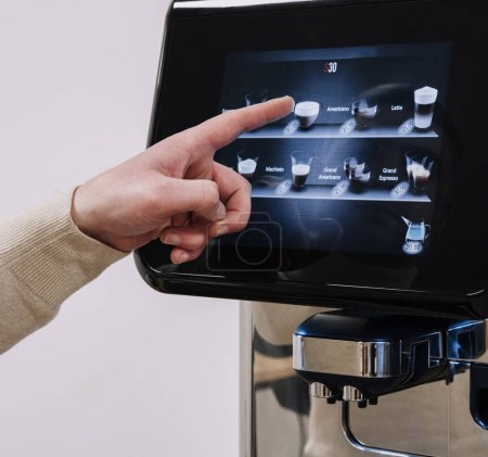 Person mit einem Finger, um Optionen auf einem fortschrittlichen Touchscreen-Display für Kaffeemaschinen auszuwählen