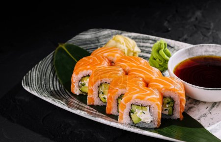 Pyszne sushi z łososia z sosem sojowym, wasabi i imbirem na czarnym tle
