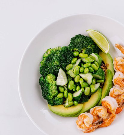 Frischer grüner Salat mit Garnelen, Brokkoli, Avocado und Limette auf weißem Hintergrund