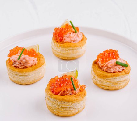 Tazas de hojaldre gourmet con tartar de salmón y hierbas, listas para servir sobre un fondo blanco