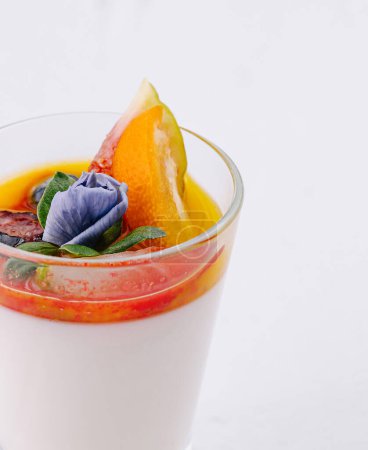 Elegant dessert of panna cotta with colorful fruit topping on a white backdrop