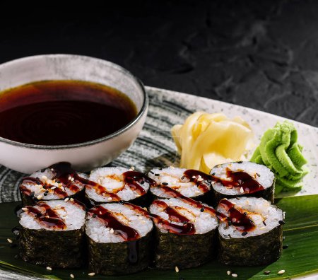 Sushi bułki z dodatkami, podawane z sosem sojowym, imbirem i wasabi na teksturowanym talerzu
