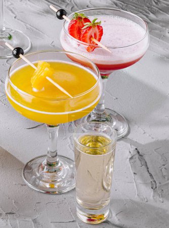 Eine Vielzahl erfrischender Cocktails mit Beilagen, die auf einer Tischplatte angeordnet sind