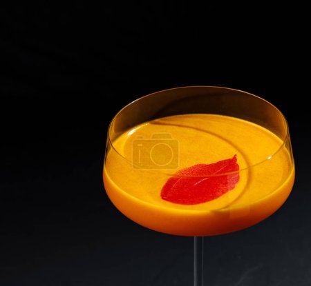 Sofisticado cóctel naranja con un toque cítrico, presentado en una elegante superficie oscura