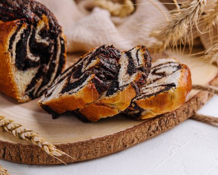 Freshly baked poppy seed swirl bread presented on a rustic wooden board with wheat ears