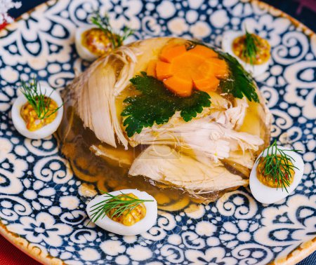 Traditionelle Gelee-Geflügel-Aspik garniert mit Gemüse auf einem verzierten Teller mit Winterdekor