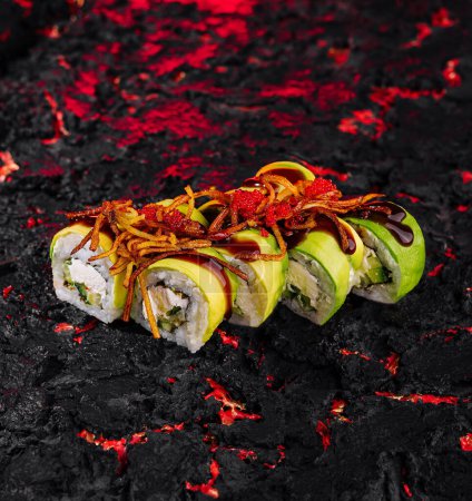 Vibrant awokado sushi roll zwieńczona pikantnym sosem na ognistym czerwonym i czarnym teksturowanym tle