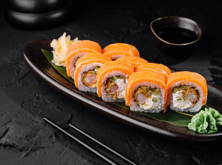 Rozkoszne sushi z łososia serwowane na eleganckim ciemnym talerzu z sosem sojowym, idealny dla azjatyckiej kuchni motywy