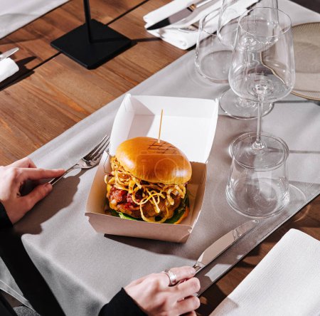 Eine Person genießt einen köstlichen Burger, der in einem stilvollen Restaurant serviert wird