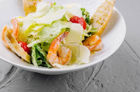 Téléchargez les photos : Salade césar appétissante avec crevettes succulentes, parmesan rasé et croûtons dorés sur une assiette blanche - en image libre de droit