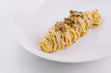Élégante portion de spaghettis garnis de truffes rasées sur une assiette élégante, fond de marbre
