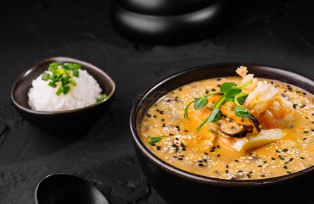 Appetitlicher Kimchi-Eintopf, serviert mit Reis auf dunklem, strukturiertem Hintergrund