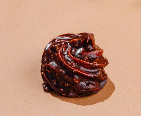 Eleganter Strudel aus glänzender Schokolade auf beiger Oberfläche mit minimalistischer Ästhetik