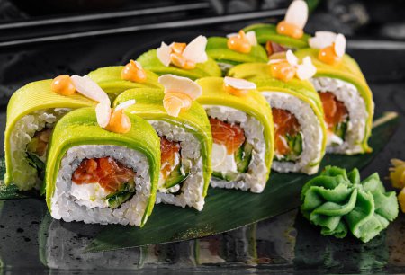 Exquisite avocado sushi rolls garnished with ginger on a stylish black plate, japanese cuisine