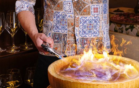 Chef bereitet Pasta im flammenden Käserad in einem Gourmet-Restaurant zu